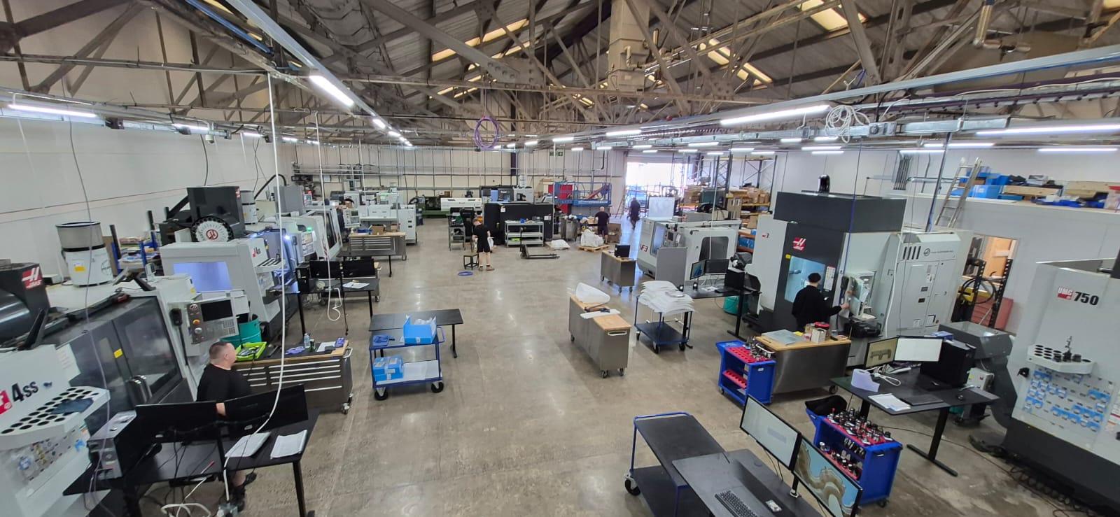 Elevated view of a busy machine shop floor with CNC mills and workstations